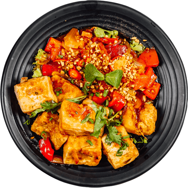 A black dish filled with a colorful assortment of fresh vegetables and bread.